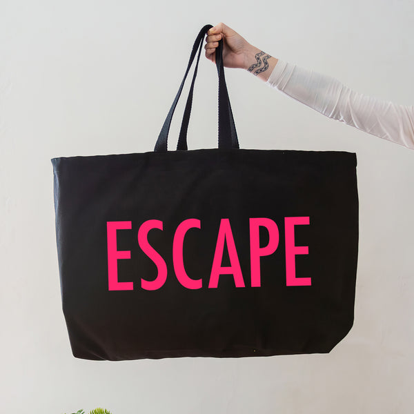black oversized tote bag with large neon pink escape text