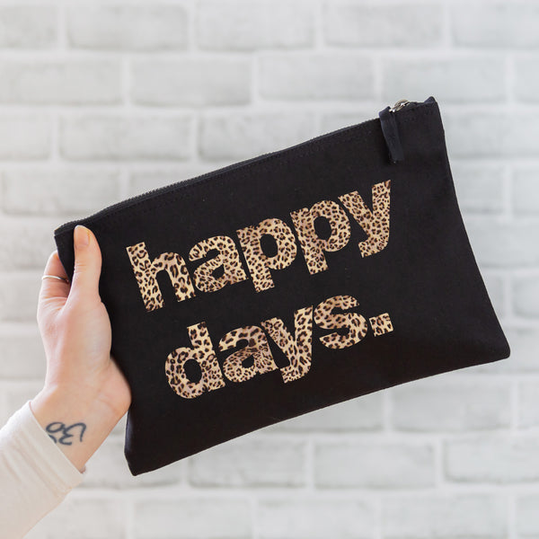 an oversized black cotton canvas pouch with the slogan 'happy days' printed in leopard print