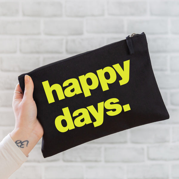 an oversized black cotton canvas pouch with the slogan 'happy days' printed in neon yellow