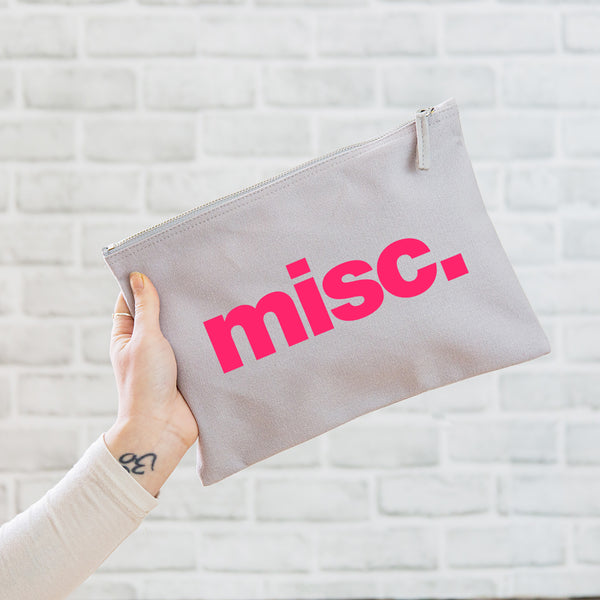 A really useful oversized canvas pouch printed with the slogan 'misc' in neon pink